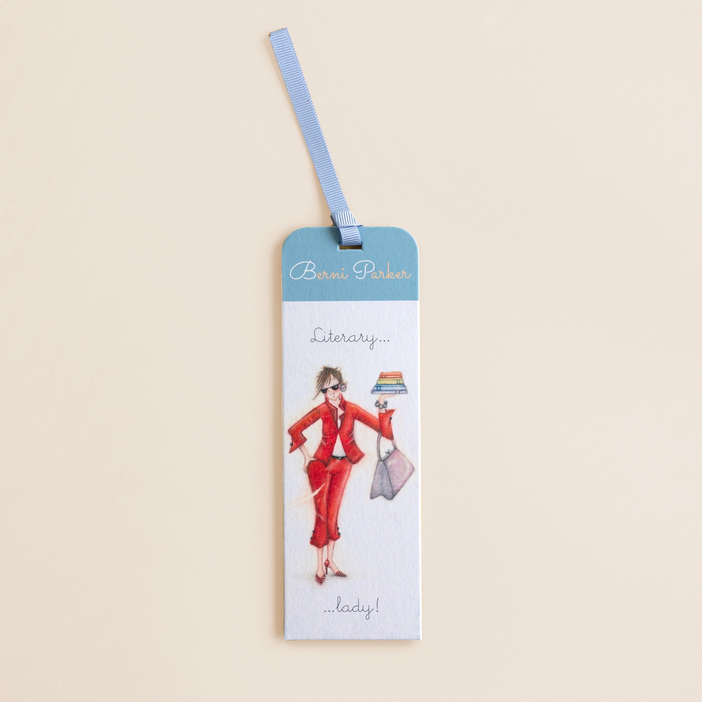 A bookmark with an illustration of a women in a red dress and a library setting, with a decorative blue ribbon at the top and text 'Literacy Lady!'