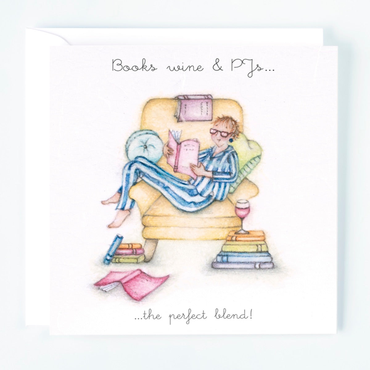 A greeting card with an illustration of a women relaxing in an armchair with a book, surrounded by wine and PJ's, with text on the card reading 'Books, wine & PJs the perfect blend!'