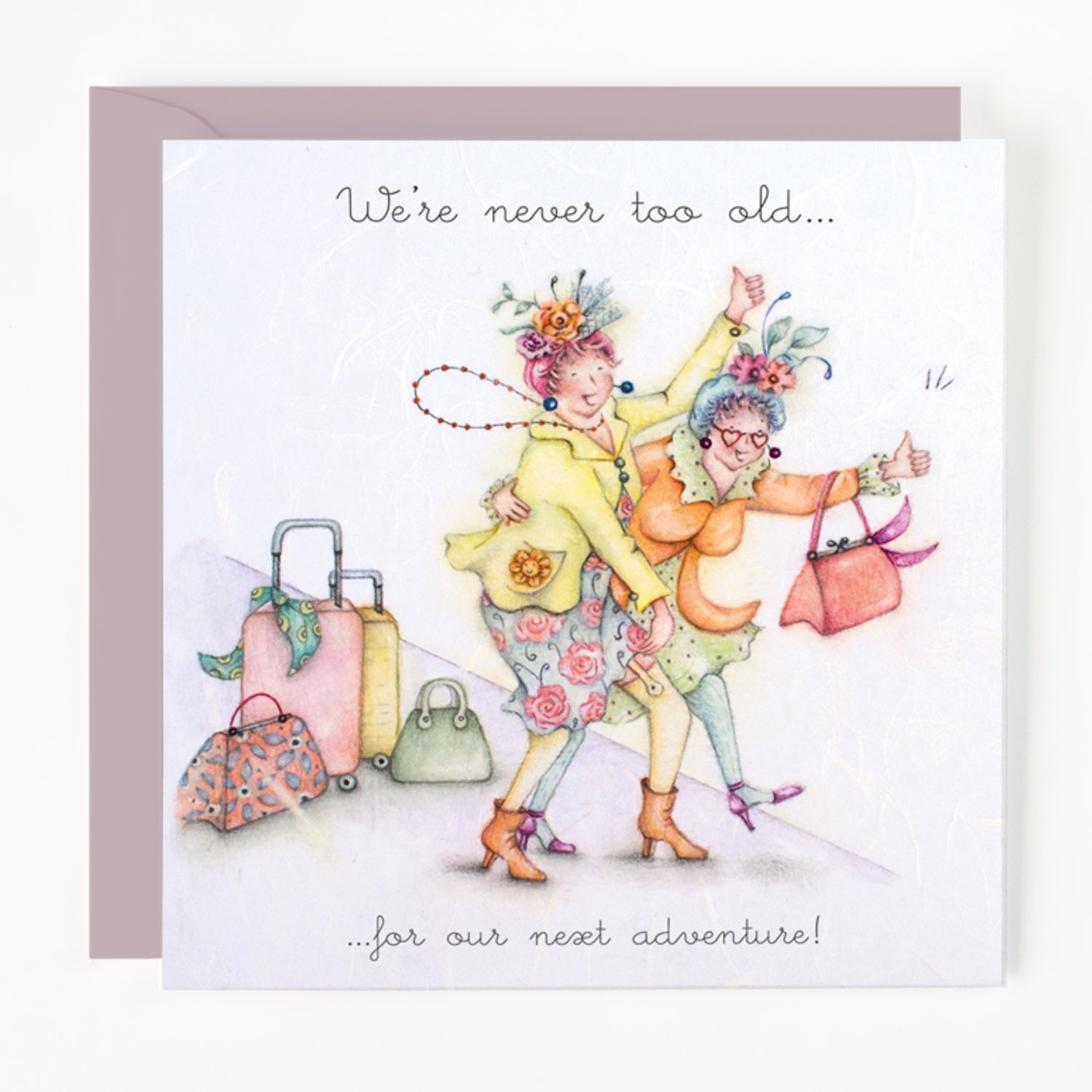 Card with two elderly women dancing, surrounded by suitcases, with text 'We're never too old... for our next adventure!'