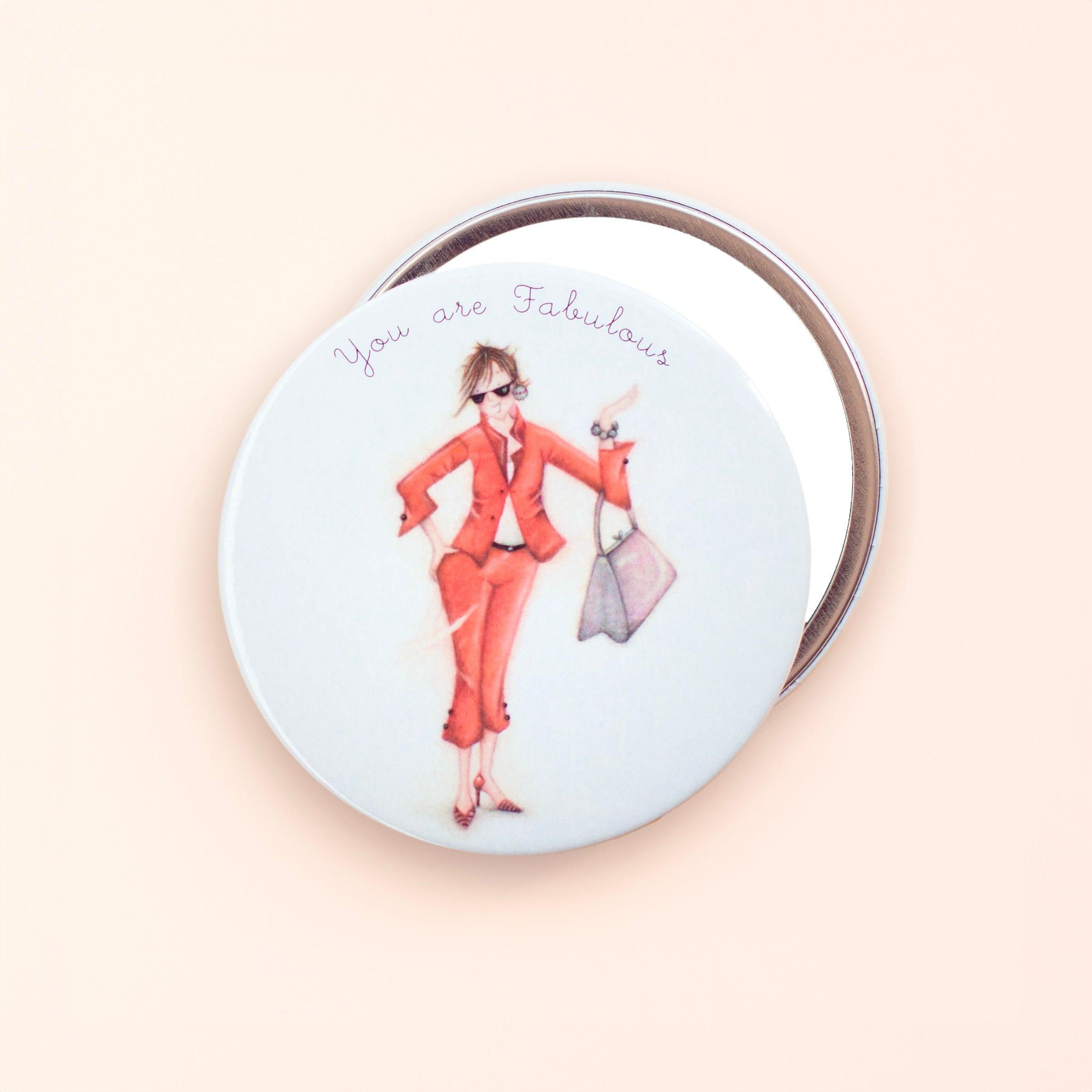 Round pocket mirror with an illustration of a woman in a red suit and the text 'You are Fabulous' on the bottom.